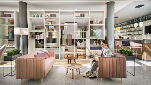 A modern lounge area with seating, a coffee bar, and a bookshelf filled with books and decorative items.