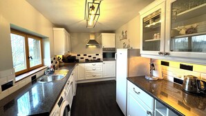 A compact kitchen with white cabinets, a built-in oven, a washing machine, and a coffee maker.