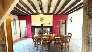 A dining area with a wooden table and chairs, a brick floor, and a red wall.
