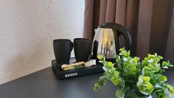 A tray with two black cups, a kettle, and a box of tea bags on a table.