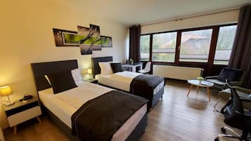 Two single beds, a desk, and a potted plant adorn this stylish room with a view.