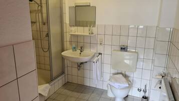 Een badkamer met een douche, wastafel, toilet en een handdoekhouder.
