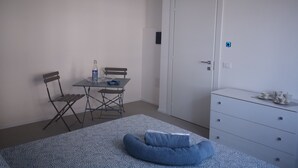 Ein Schlafzimmer mit Bett, Schreibtisch, Stuhl, Kommode und Kleiderschrank.