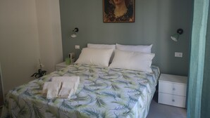 Ein Schlafzimmer mit einem Bett, zwei Nachttischlampen, einem Nachttisch, einer grünen Wand und einem Gemälde.