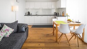 Un espacio habitable compacto con kitchenette, zona de comedor y sofá.
