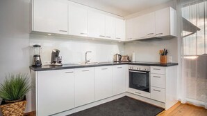 Eine moderne Küche mit weißen Schränken, einem eingebauten Backofen und einer Kaffeemaschine.