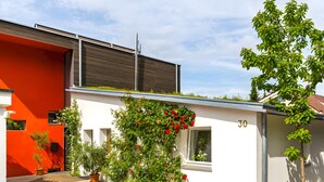 Ein modernes Gebäude mit roter und weißer Fassade, einem Ziegelweg und der Nummer 30 an der Wand.