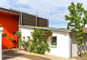 A modern building with a red and white facade, a brick pathway, and a number '30' on the wall.