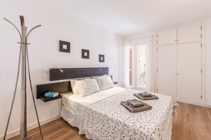 Een slaapkamer met een bed, nachtkastje, kledingkast en een raam.