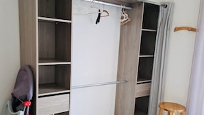 Garderobeskab med åbne hylder, bøjlestang og en skammel.