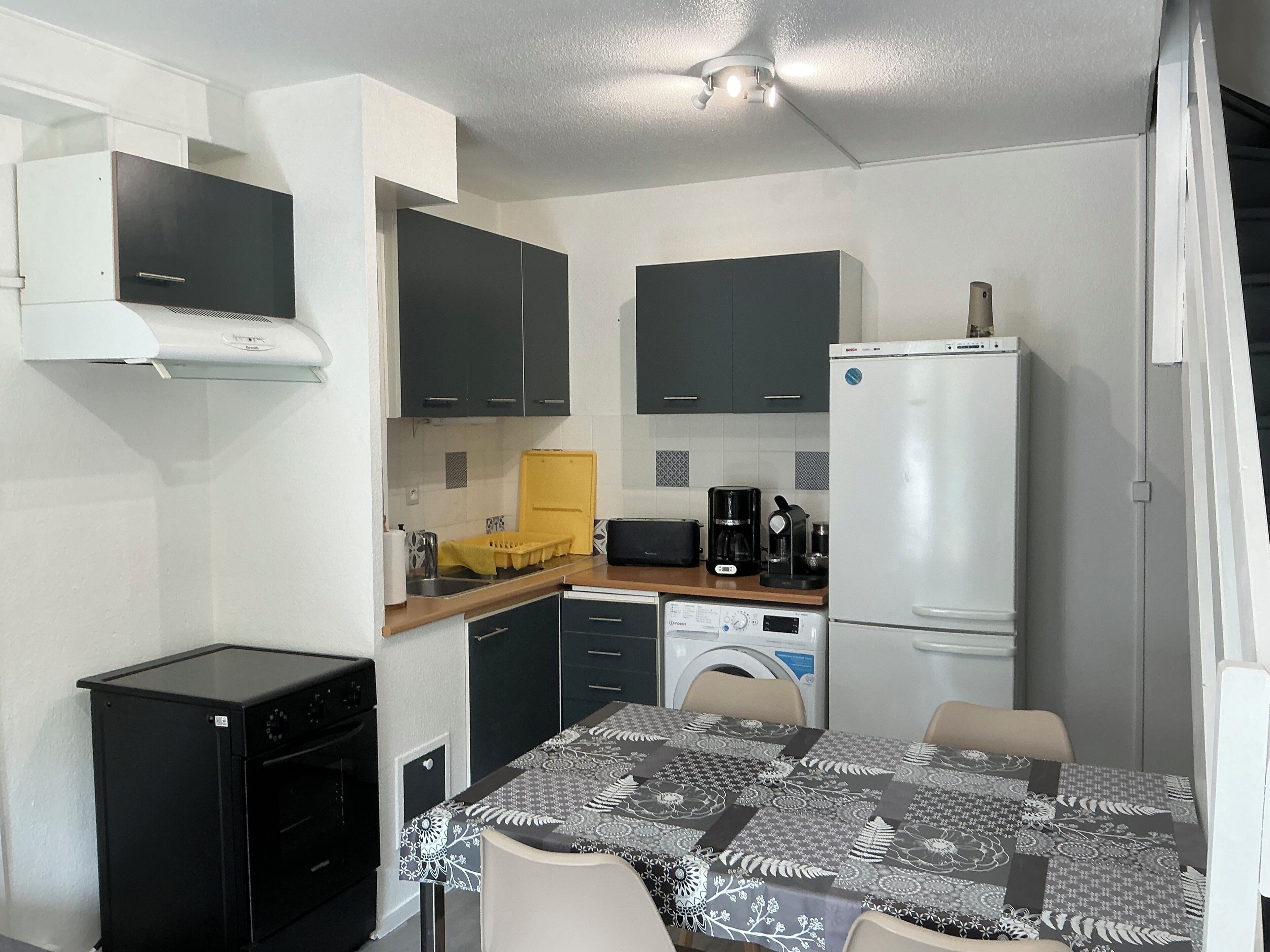 A compact kitchen with a microwave, coffee maker, and a refrigerator.