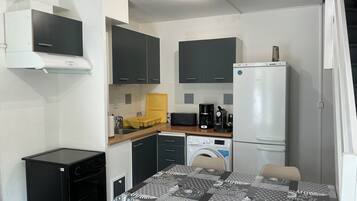 A compact kitchen with a microwave, coffee maker, and a refrigerator.