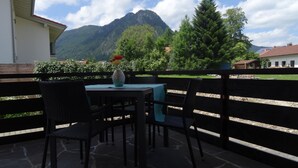 A patio with a table and chairs, a vase with flowers, and a mountain view. - Quietly located vacation apartment in Pfronten (Pfronten)