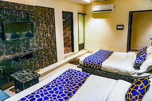 A hotel room with two beds, a TV, and a marble wall. - Hotel Privilege Villa (Ahmedabad)