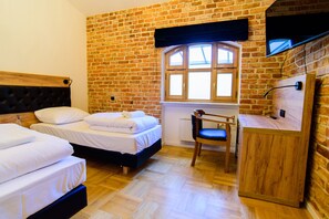 A room with a brick wall, two beds, a desk, and a chair. - Lord Jack Apartments (Rzeszów)
