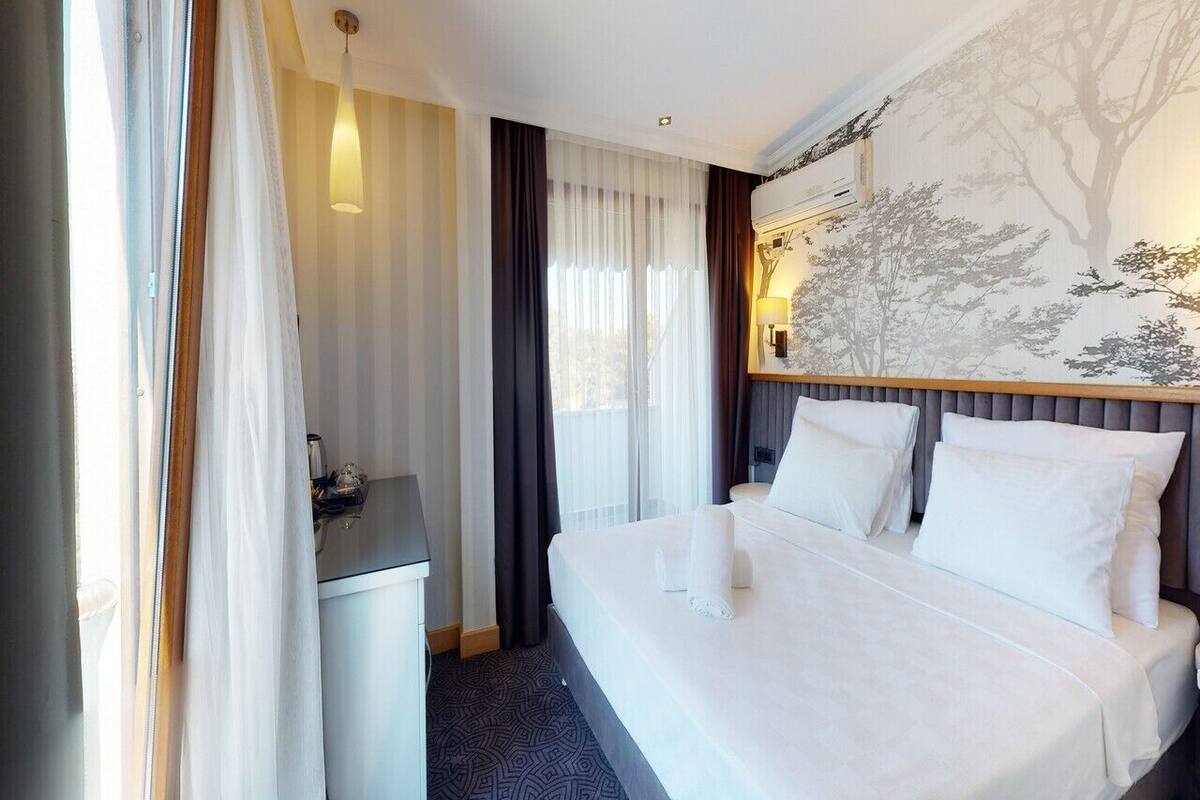 Une chambre d’hôtel avec un lit, une table de chevet et une lampe fixée au mur.