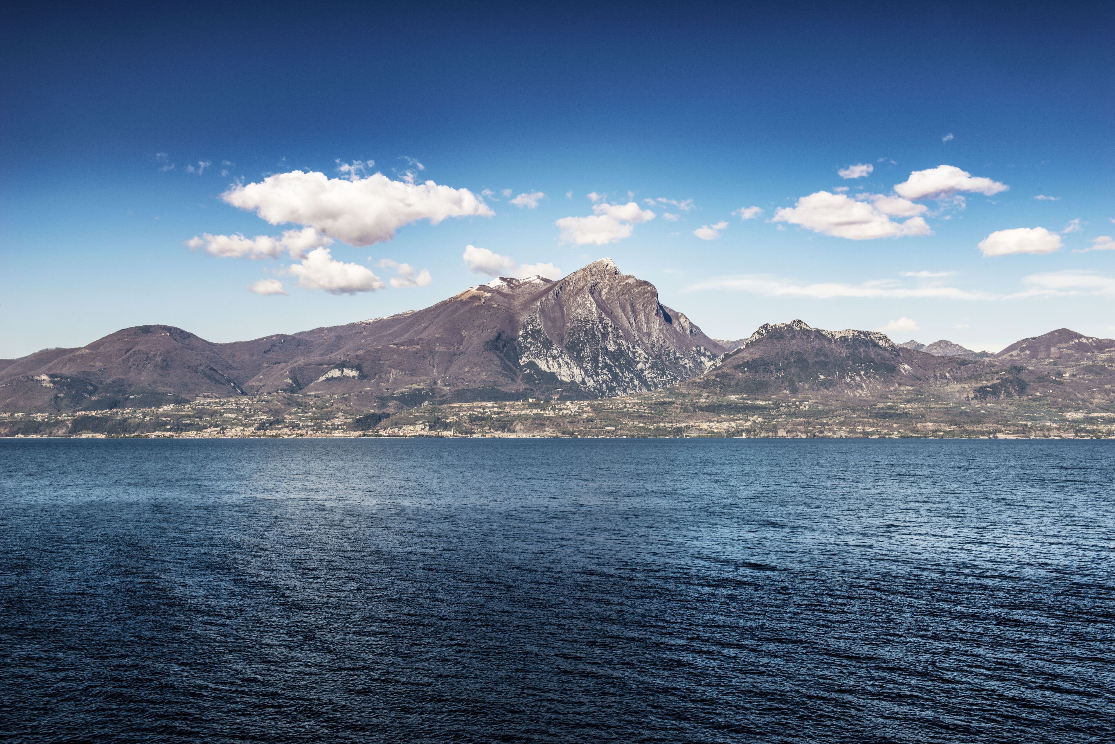 Een kustlandschap met bergen op de achtergrond en een rustige zee op de voorgrond.