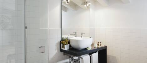 Une salle de bain moderne avec une douche à parois de verre, un lavabo blanc et un plan de toilette noir.