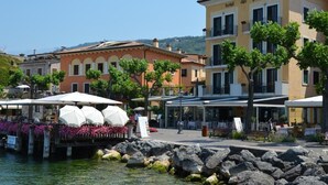 A waterfront hotel with outdoor seating, a covered patio, and a view of the water. - Hotel del Porto (Torri del Benaco)