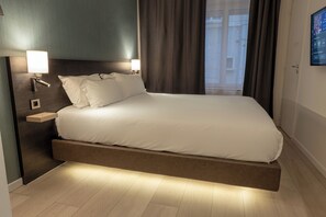 A modern hotel room with a bed, bedside lamps, a nightstand, and a view of the outside. - Five Resort Cholet Centre (Cholet)