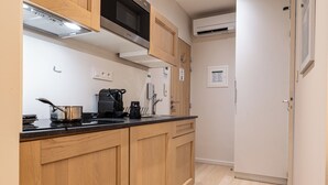 A kitchen with wooden cabinets, a microwave, a coffee maker, and a sink. - Five Resort Cholet Centre (Cholet)