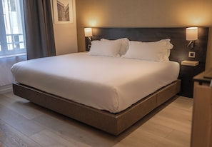 A large bed with a wooden frame, two bedside lamps, and a picture on the wall. - Five Resort Cholet Centre (Cholet)