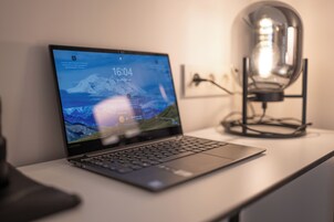 Un ordinateur portable sur un bureau, avec une lampe en arrière-plan.