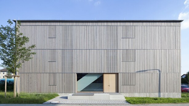 Een modern gebouw met een plat dak, een ruime glazen ingang en een eenvoudig, rechthoekig ontwerp.