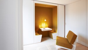 Een moderne kamer met een witte garderobe, een klein wit tafeltje en een mosterdgele stoel.