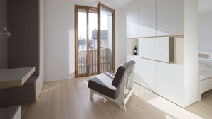 Een moderne, minimalistische kamer met een ingebouwde bank, een klein wit kastje en een glazen schuifdeur die uitkomt op een balkon.