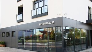 A modern building with a glass facade and the sign "RESTAURACJA" indicating a restaurant. - Lemon Plaza Poznań (Poznan)