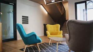 A modern interior with a blue and yellow chair, a grey armchair, and a small table on a patterned rug. - Lemon Plaza Poznań (Poznan)