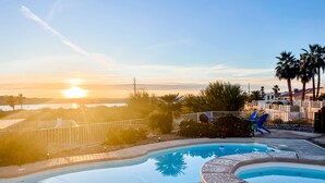Ein Schwimmbad mit Blick auf den Sonnenuntergang und Palmen.