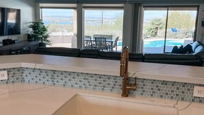 Eine Küche mit einer großen Kochinsel, Deckenventilator und Blick auf Pool und Terrasse.