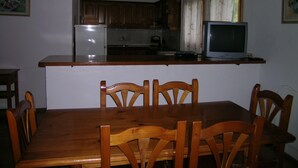 Eine kleine Küche mit Holzausstattung, einem Kühlschrank, einer Mikrowelle und einem Fernseher auf einer Holzaarbeitsplatte.
