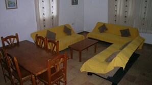 Ein Zimmer mit zwei gelben Sofas, einem Holzesstisch und Stühlen.