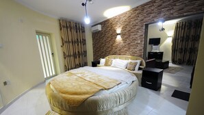 Un dormitorio moderno con una cama grande, una pared de ladrillo decorativa, un televisor de pantalla plana y un escritorio pequeño.