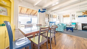 Een eetruimte met een houten tafel en stoelen, een geel kastje en een blauw decoratief object aan het plafond.