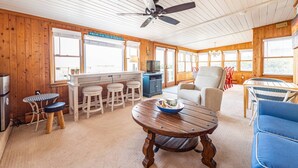 Interior de cabana de madeira com área de jantar, bar e assentos.