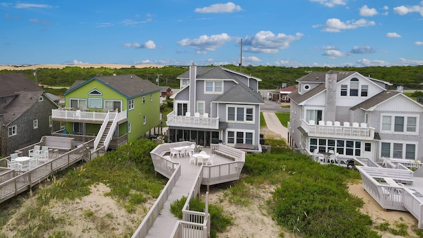 Una zona residenziale sul litorale, con diverse case caratterizzate da balconi, ponti di legno e una spiaggia sabbiosa sullo sfondo.