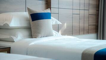 A hotel room with a neatly made bed, a nightstand, and a headboard with a wooden panel design.