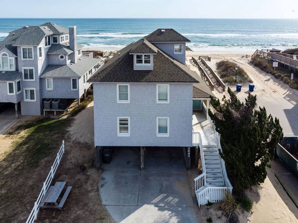 Een twee verdiepingen tellend huis met garage, een overdekte veranda en uitzicht op de oceaan.