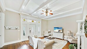 Un salon spacieux doté de planchers en bois franc, d’un canapé beige, d’une table basse, d’un téléviseur et d’une cheminée.