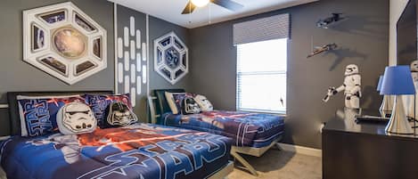 A bedroom with two beds, Star Wars themed bedding, a ceiling fan, and Star Wars figurines.