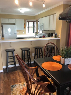 A kitchen with white cabinets, a refrigerator, a sink, and a window with blinds.