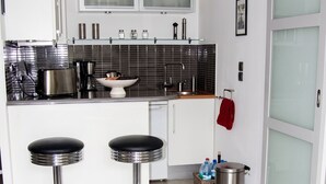 A modern kitchen with a central island, bar stools, and a glass table.