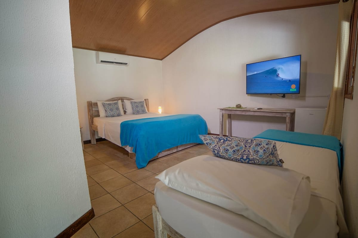 A bedroom with two beds, a TV mounted on the wall, and a small table.