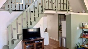 A living room with a wooden entertainment unit, a flat-screen TV, and a staircase with heart-shaped cutouts.