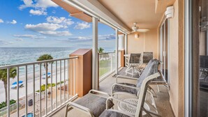 A balcony with a view of the ocean, a ceiling fan, and outdoor furniture.