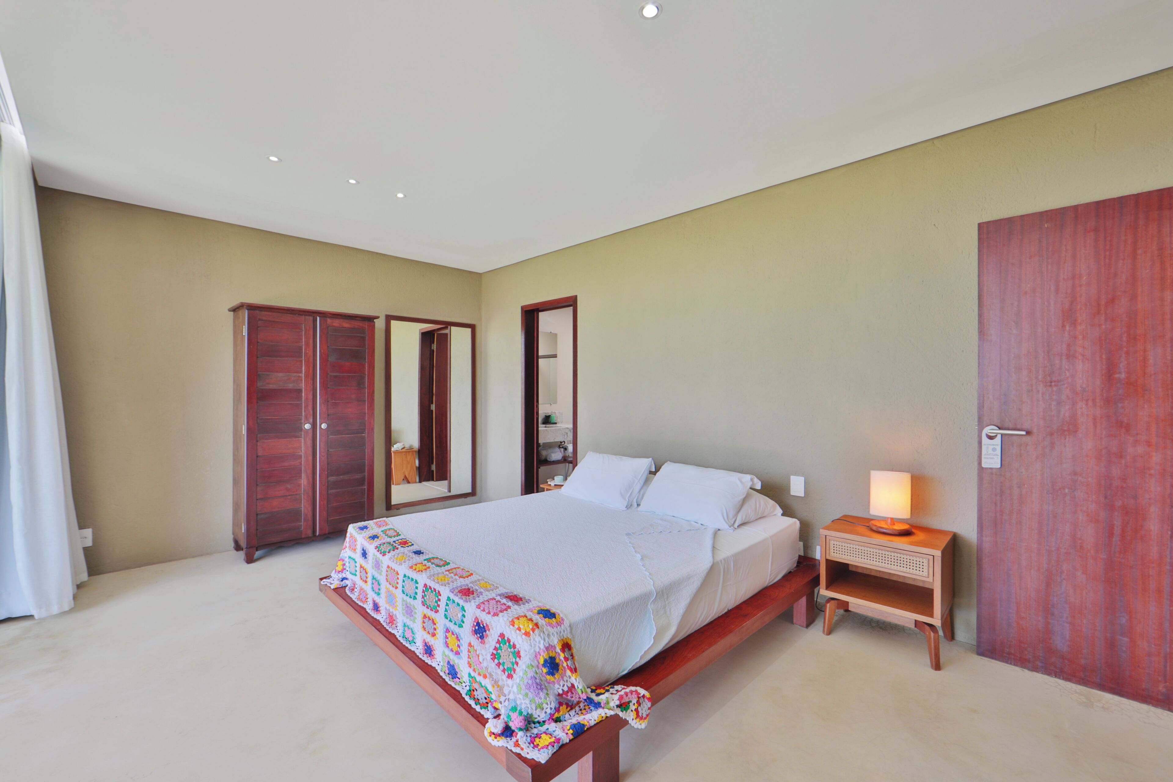 Un dormitorio con cama, mesita de noche, armario y una puerta.